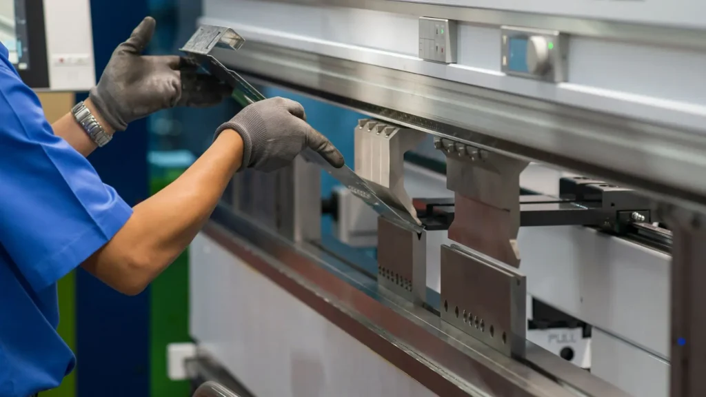 Operator formuje arkusz metalu na prasie krawędziowej, urządzenie precyzyjnie wygina blachę zgodnie z wymaganiami produkcyjnymi w procesach przemysłowych.