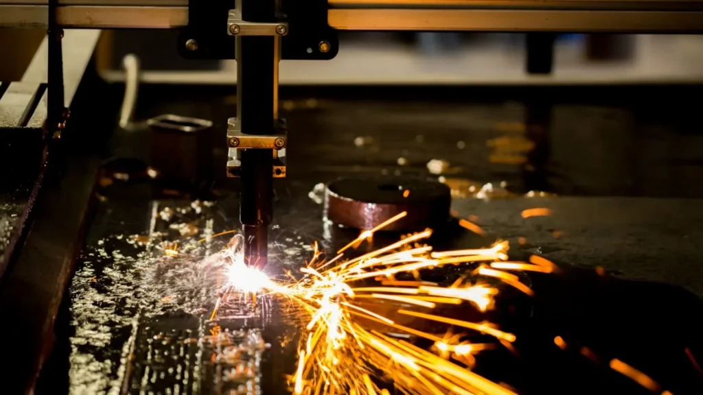 Proces cięcia plazmowego blachy z widoczną dyszą palnika generującą intensywną wiązkę plazmy i rozpryskujące się iskry podczas pracy wycinarki.